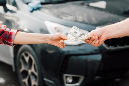 An exchange of cash between two people, likely a down payment or payment for a vehicle.