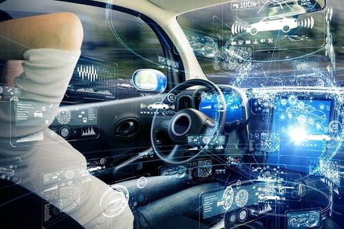A driver in a vehicle surrounded by augmented reality overlays showing data, sensors, and other vehicles, representing advanced driver assistance systems.