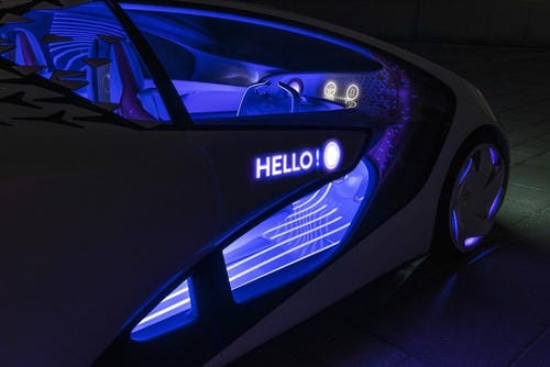 A futuristic concept car with blue interior lighting displaying "HELLO!" on its side.